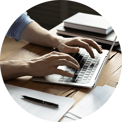 A close up of someone typing on a laptop on a desk.
