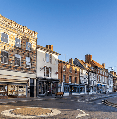 A wide shot of a busy high street with a lot of semi commercial properties down it.