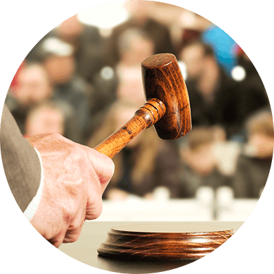 A man holding a gavel in front of a blurred crowd in the background.