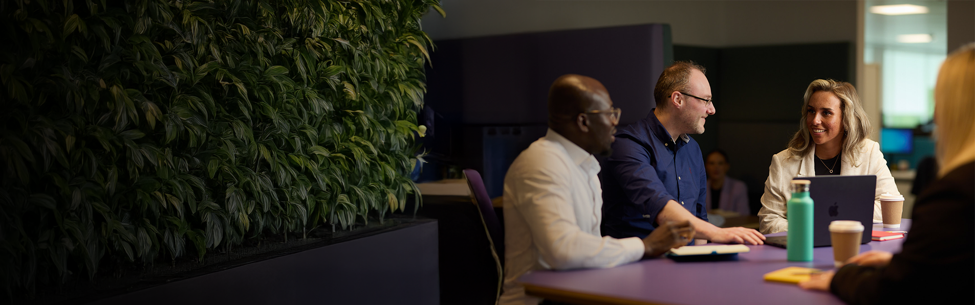 A group of men and women sat down talking to each other in an office space.